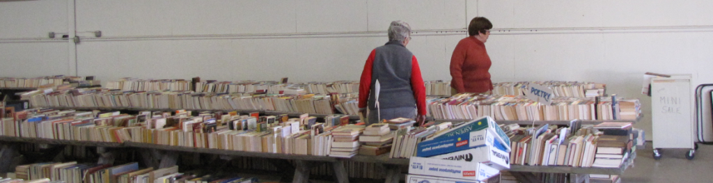 two women sorting stacks of donated books on long tables