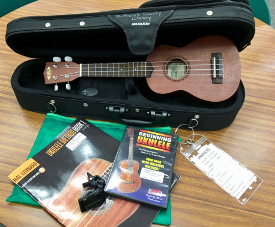 Photo of open case with ukulele inside and ukulele book and DVD on a table beside the case
