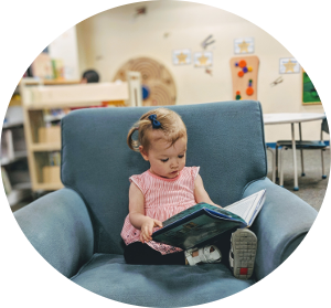 little girl reading a book in a blue chair