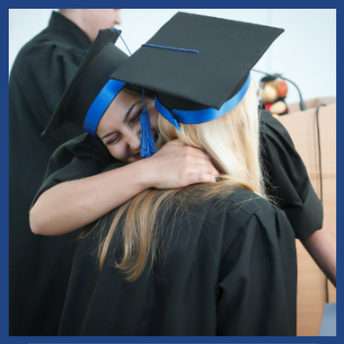 two graduates in cap and gown hugging