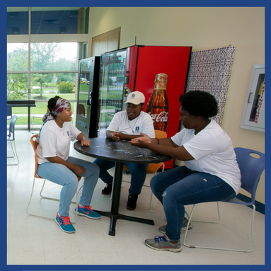 three teenagers sitting at a table talking