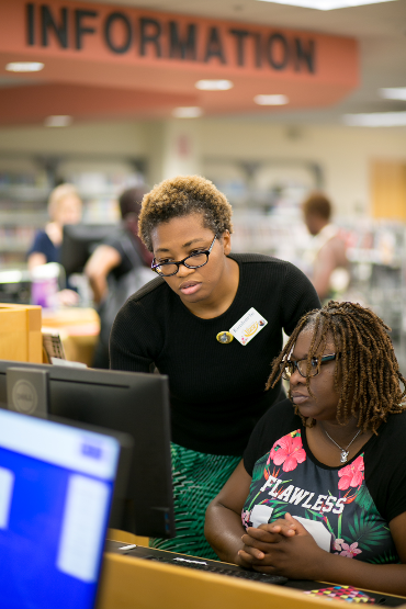 woman sitting at computer with staff member standing behind her