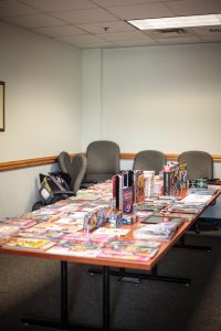 A long conference table covered in comic books