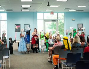 Cosplay contest participants standing at the front of a crowd  holding numbers for voting