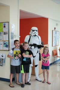3 children standing with person dressed as a storm trooper