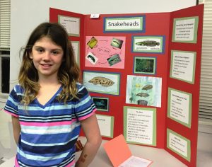 Girl standing in front of a science fair project about snakeheads