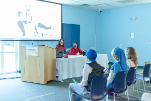 2 cosplays sharing slides to an audience