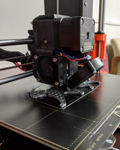 Close up photo of a 3D printer extruder printing a silver cat