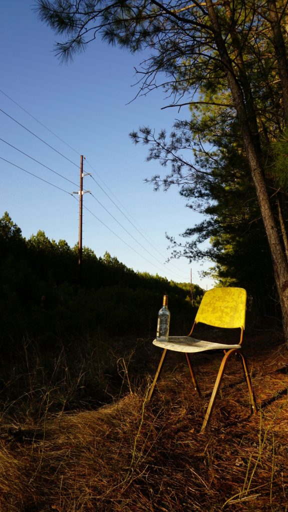 photo of a yellow chair with a water bottle on it taken outside by a telephone pole