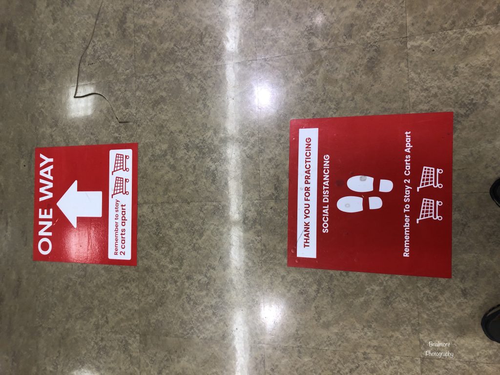 two red stickers on the floor encouraging social distancing