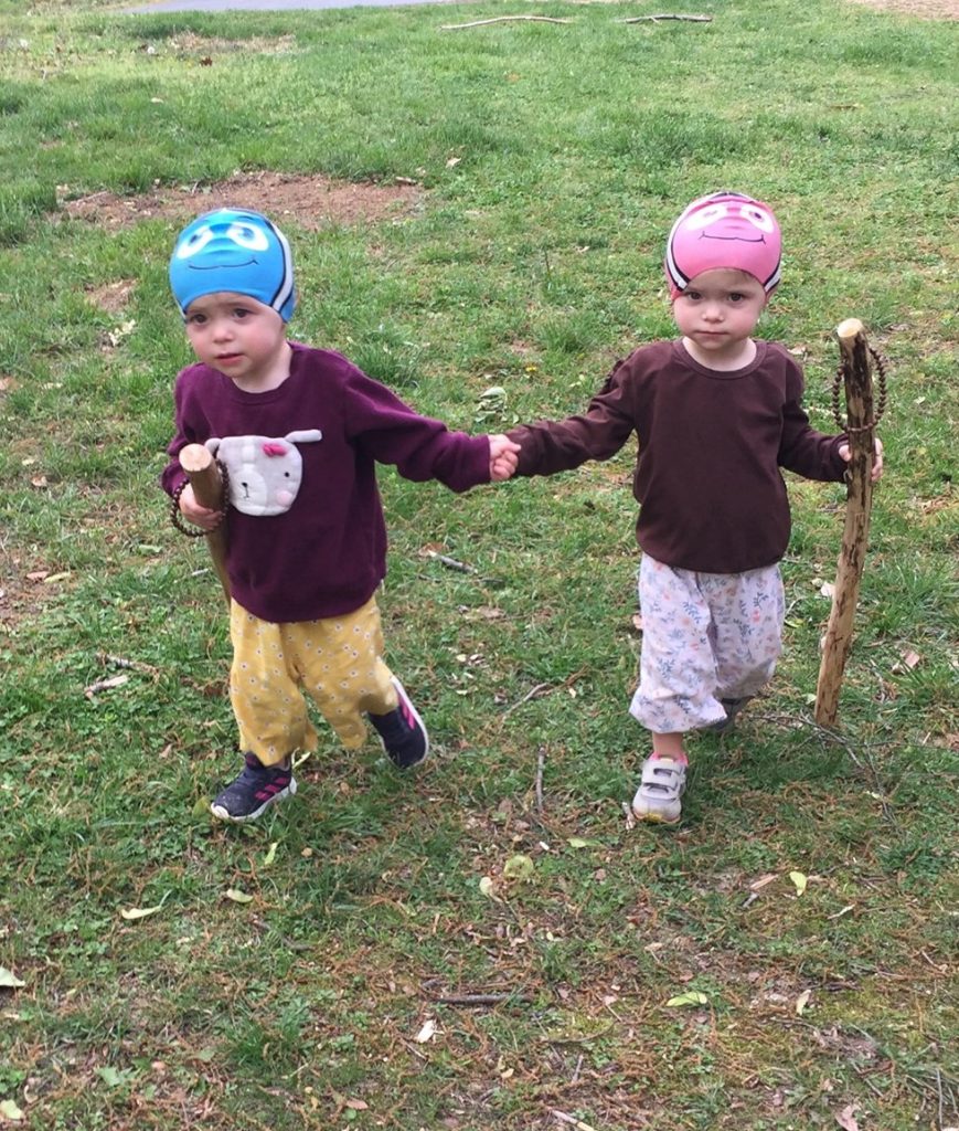 two children in swimming caps holding hands and walking outside