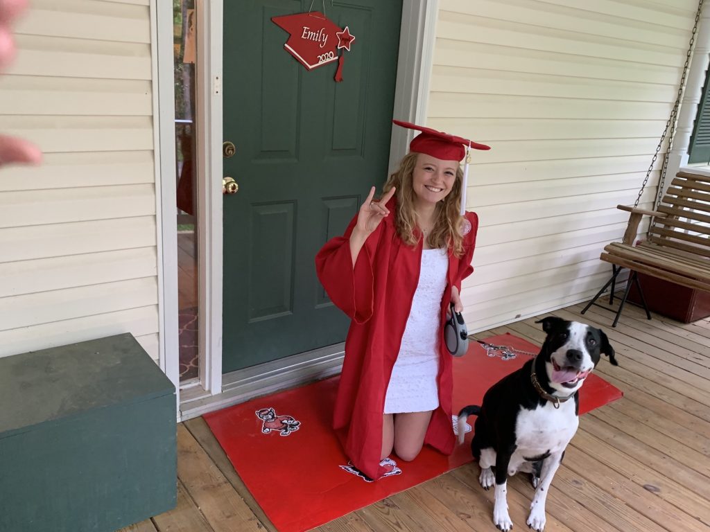 a girl in a graduation cap and gown with a black and white dog