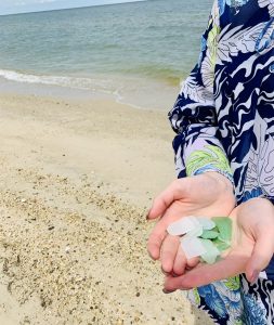 A woman's hands holding sea glass on a beach