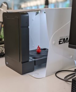 Black 3D scanner in a lightbox with a red boat on the turntable