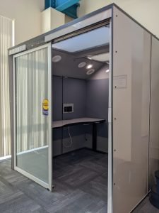Large square booth with glass front and a table inside