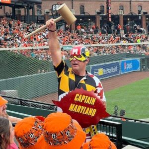 Man in a Captain Maryland costume holding a large crab mallet in the crowd at Camden Yards