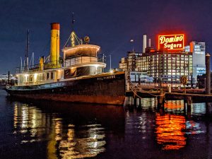 A large boat in the water in front of a large neon sign reading Domino Sugars