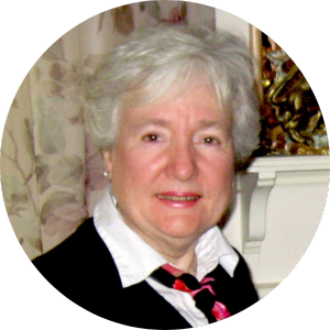 Headshot of a white woman with short white hair wearing a white colored shirt and black sweater