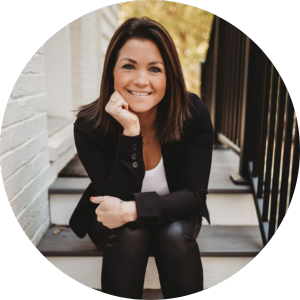 A white woman with long brown hair sitting on steps with her hand under her chin