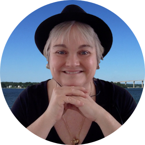 Headshot of a white woman in a black hat with the water and a bridge behind her