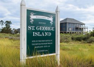 Welcome to St George Island sign in the foreground, with a large blue house in the background