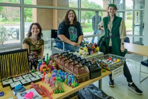 Vendors sitting behind their table of items, including jewelry, treasure boxes, and mystery items