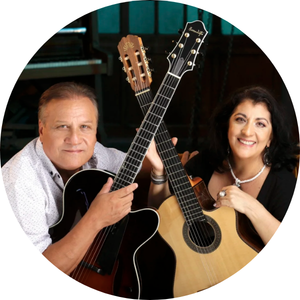 A man and woman holding guitars, smiling at the camera