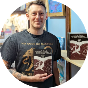 Chris Woolsey stands in front of a bookshelf holding a book titled The Wail