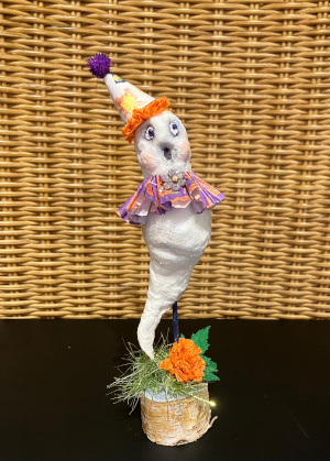 a small white three-dimensional ghost made of cotton balls and glue, wearing an orange and purple party hat and purple decorative ruff made of paper