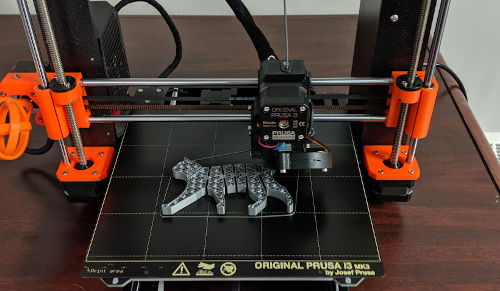 A 3D printer printing a grey flexi- cat