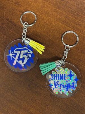 Two keychains with acrylic inserts, one with a diamond and 75th and one reading Shine Bright