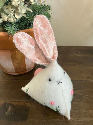 A white felt triangle bunny with pink ears