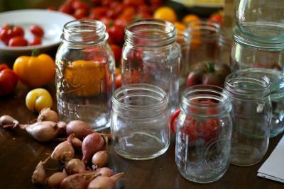 Empty canning jars surrounded by tomatoes and shallots