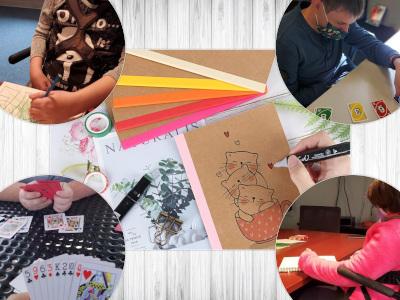 A collage. Paper and a hand drawing three kittens in a mug in the center. In the corners, a close up of a hand of cards, a person in a pink sweater sitting at a table writing in a notebook, a young man wearing a mask playing Uno, a person coloring