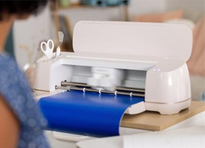 A Cricut vinyl cutter cutting blue vinyl