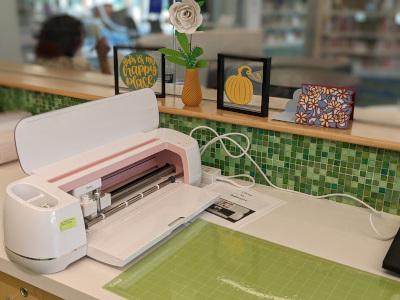 A Cricut cutting machine, open with a green mat next to it