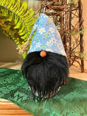 A gnome head with black mustache and beard, wearing a blue hat with flowers on it