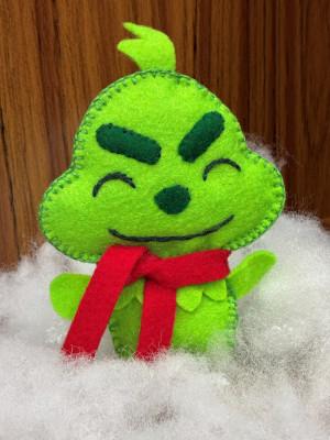 A felted green plushie inspired by the Grinch, wearing a red scarf