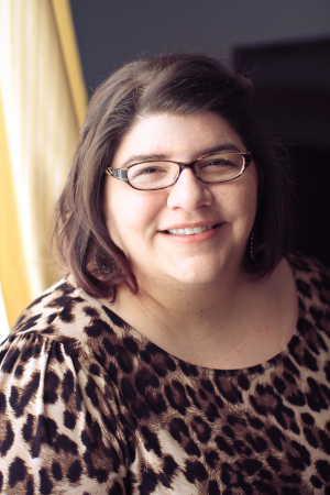 Woman with brown hair and glasses wearing a leopard print shirt