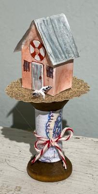 A decorated paper house sits on top of a wooden platform