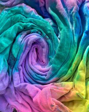 A pinched and swirled item of clothing dyed purple, green, blue, yellow, and pink