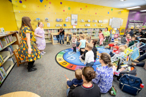 a group of children and adults at storytime with two librarians