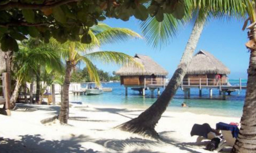 Photo of a beach, water, and two tropical buildings