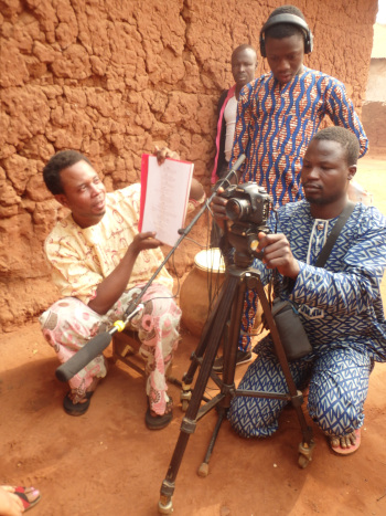 four African men in traditional clothes setting up a shot for a movie