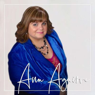 woman with dark hair wearing a blue jacket and necklace, Ann Aguirre's signature over the photo