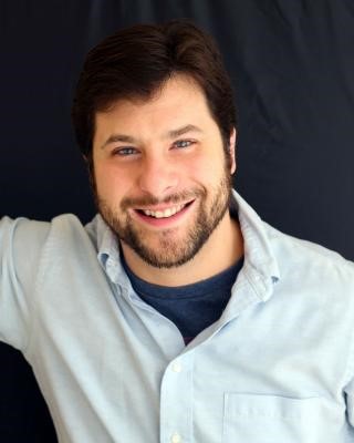 Headshot of a Ronald Malfi, a man with dark hair and beard wearing a blue collared shirt